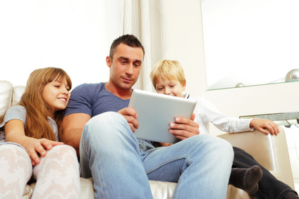Father with children playing on tablet computer at home